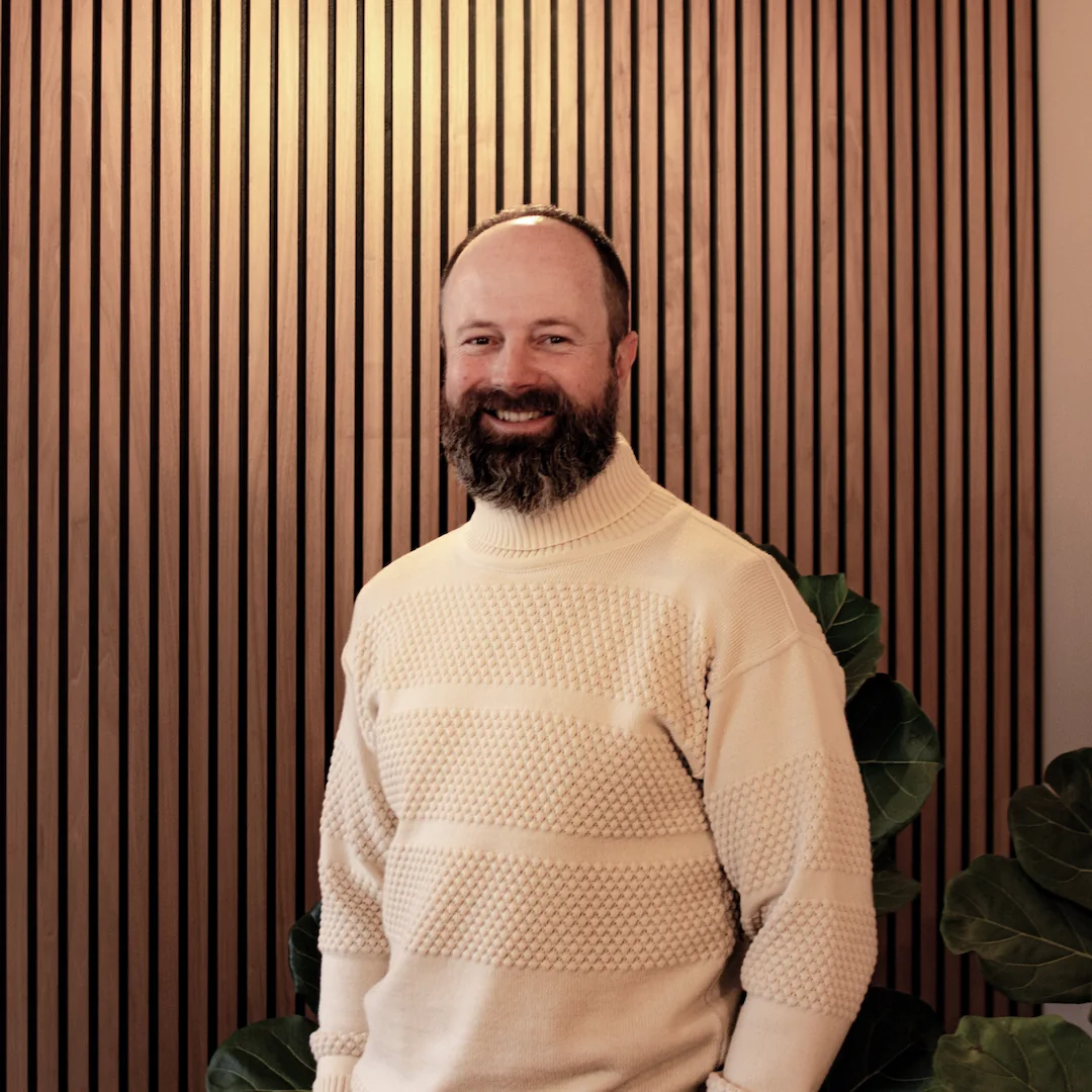 A portrait of Andrew, a business advisor on the board of Invisaid. He is standing with a cream sweater on.